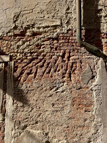 A sunny wall, with sand-coloured plaster crumbling away to expose terracotta brick. What makes the texture interesting are deep scratch marks in the brick in the centre of the photo, which look like giant furious claw marks, as if an angry Wolverine has taken out his frustrations on the wall with both hands. A bent drainpipe frames the top right hand corner, and throws a black shadow on to the wall.