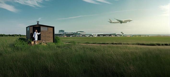 A woman in the doorway of a sauna at Helsinki Airport. This is a wide shot, and a jet airliner is taking off in the background.