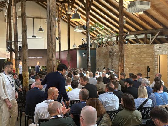 Audience seated in a rustic venue with wooden beams, waiting for a session to begin at an Umbraco event.
