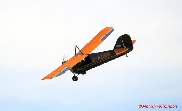 Aeronca C3 flies through a grey sky at an air display