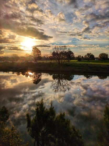 Another photo of the sunset, this time a little to the right. The trees on the left are not visible, but there aee more trees visible on the far bank.