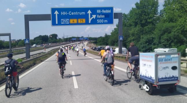 Fahrräder auf der Autobahn A255 unter einer Schilderbrücke mit Richtungsangabe "Hamburg-Centrum".