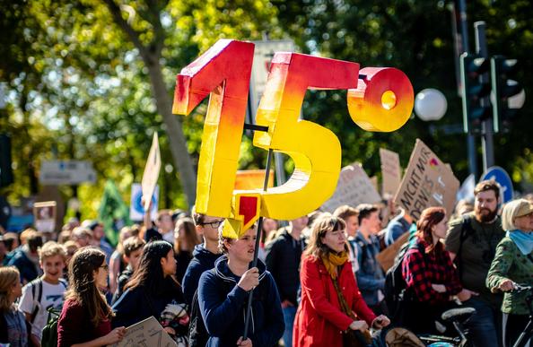 Klimaprotest, eine junge Person hält eine große 1,5° hoch