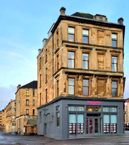 Blonde sandstone tenements lining a Glasgow Street.
