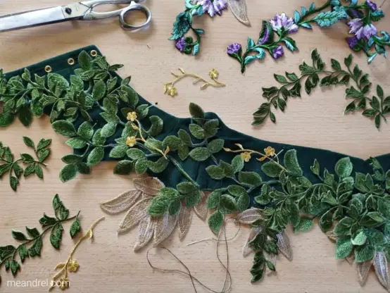 Photo d'une table où sont étalées la ceinture verte et tous ses éléments de déco en cours de pose à la main.