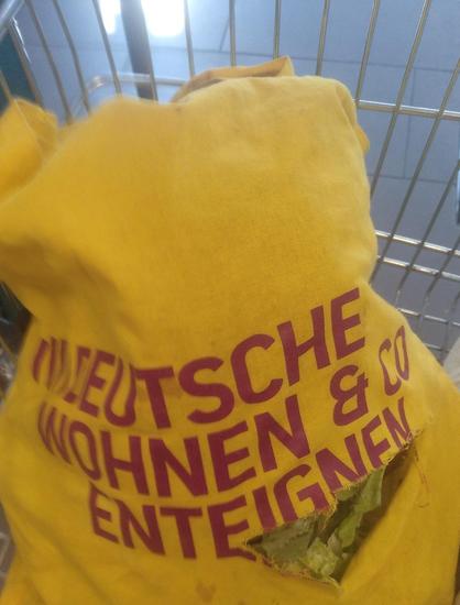 Gelber Stoffbeutel mit lilaler Aufschrift: Deutsche Wohnen & Co enteignen unter eignen ist er eingerissen.