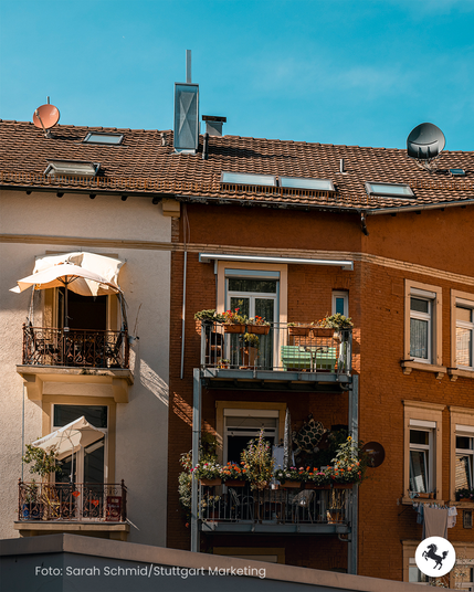 Vier kleine Balkone an einer Häuserfassade in Stuttgart-West mit Pflanzkübeln, Sitzpätzen und Sonnenschirmen.