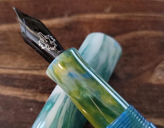 Black plated fountain pen nib engraved with a nibwolf character.