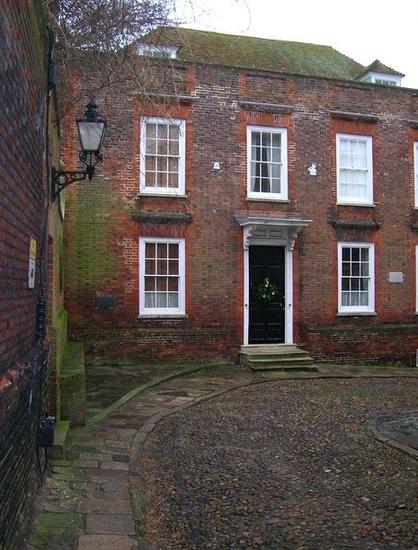 A solid-looking Georgian house with a curving pebble drive and a flagged path to the front door,