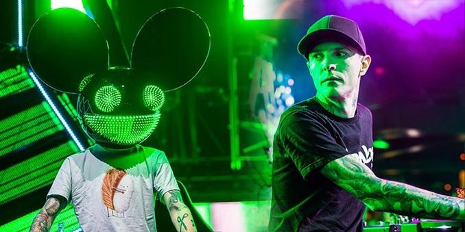 Deadmau5 wearing his iconic LED mouse helmet while performing as a DJ, with colorful stage lights in the background.