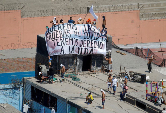 Reclusos del penal de Lurigancho sostienen una pancarta que dice "Queremos pruebas de COVID-19, tenemos derecho a la vida" durante una protesta tras un motín en el penal Miguel Castro Castro en Lima, Perú, el 28 de abril de 2020. Nueve reclusos murieron en el motín, que estalló para exigir mejores medidas sanitarias y atención médica para el coronavirus, según las autoridades penitenciarias del país. Desde el inicio de la pandemia en 2020 y durante varios años, los presos y sus seres queridos se movilizaron en todo el mundo para protegerse del COVID-19.
