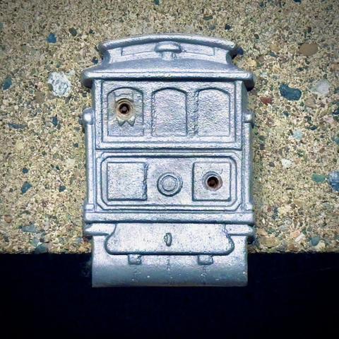 A close-up view shows a metallic streetcar design screwed down to the concrete ledge beneath it.