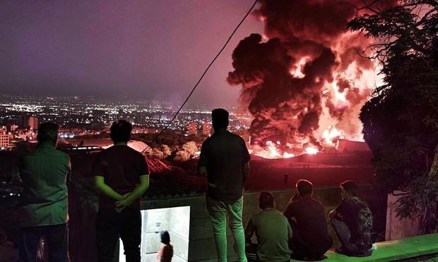 Un grupo de personas observan el fuego y el humo de un ataque israelí contra el depósito de petróleo de Shahran, el 15 de junio de 2025, en Teherán. (Getty Images)