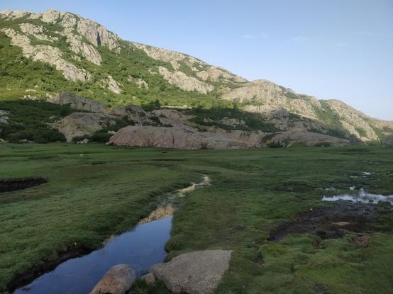 Photo d'une flaque dans une prairie entourées de montagnes