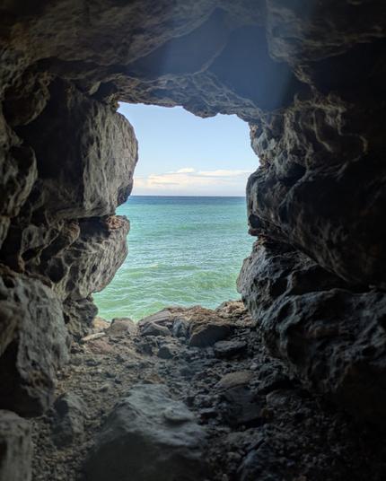 Foto di un riquadro incorniciato in una roccia di uno scorcio di mare che dal verde all'azzurro.