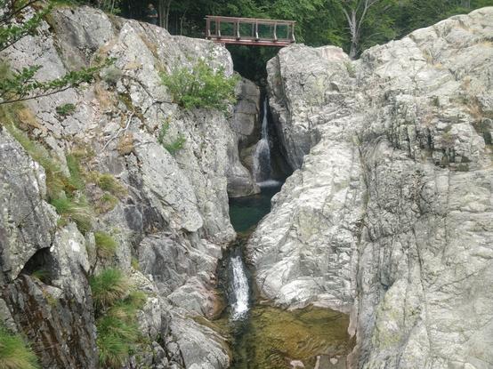 Photo d'une passerelle au dessus d'une cascade avec des marmites