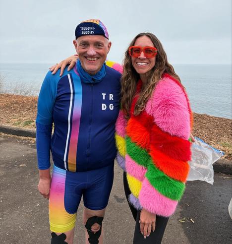 Me in a bicycle kit and Cailin in a multi-colored long coat at a rest stop on the beach.