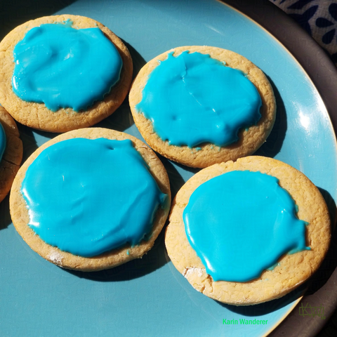 Photo of a blue plate with several iced ginger cookies arranged in a  diamond. The icing and the plate are very similar shades of turquoise.