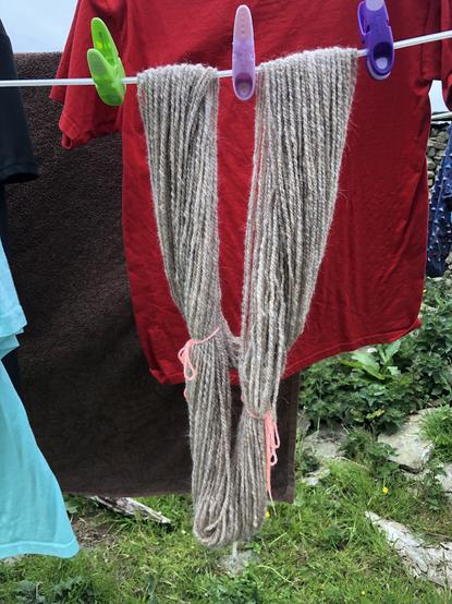 A skein of yarn hanging on a washing line along with some clothes