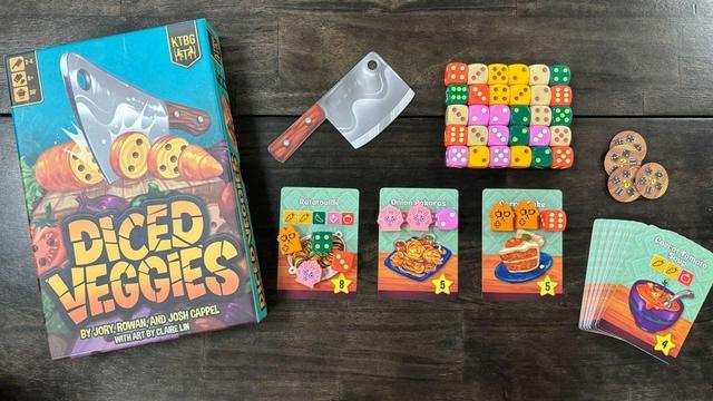 Components for the game Diced Veggies. Our cat and hedgehog hireling meeples are fooling around as ingredients with the game's dice to fulfill recipe cards.