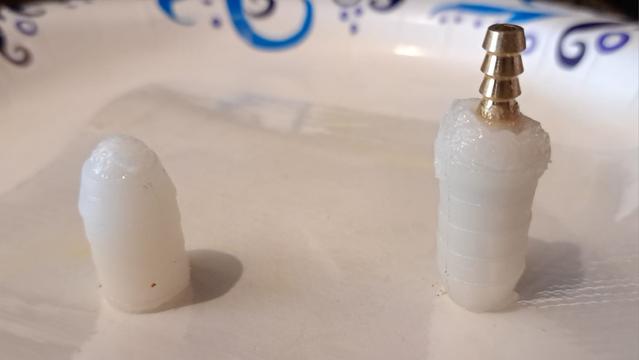 Two test parts that will eventually become flow restrictors for my tail water ballast tank. 

Both parts are half of a hose (splicing) barb, filled with thickened epoxy. The right part has a smaller brass hose (splicing) barb placed inside.

The left part will need a small diameter hole drilled in the epoxy.

After the epoxy cures, the parts will be tested to see if they leak.