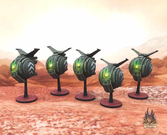 A unit of five drones in a desert setting. They are spherical with stabalising fins at the top, in a greend drab scheme with cheverons on the sides