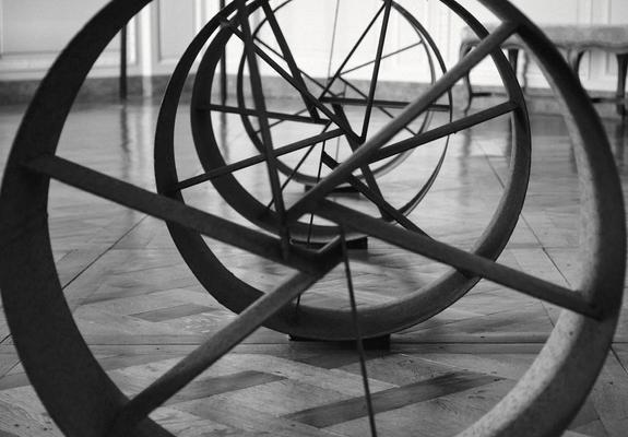 Photo en noir et blanc d’un alignement de cylindres métalliques avec des branche en leur intérieur qui forment une espèce de spirale