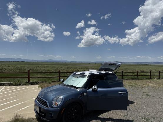 My MINI Cooper parked at Maxwell National Wildlife Refuge, New Mexico for a POTA activation. Blue, partly cloudy skies are visible.