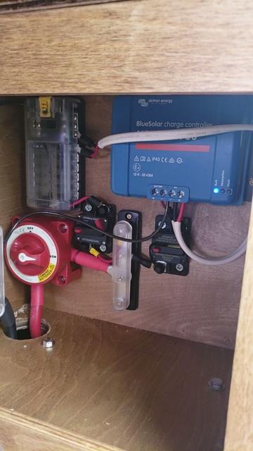 A variety of electronic components are mounted in a wooden box. The "Bulk" light on the Solar Charge Controller is lit up, indicating the battery is being charged.