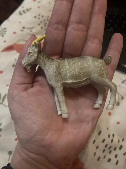 A rubber toy figurine of a goat, a few inches across