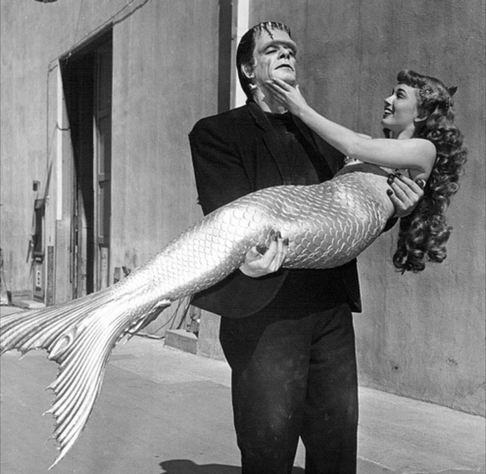 Frankenstein's monster carries off a mermaid. Both seem quite pleased with the situation.