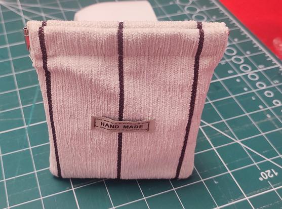 A- coin puch, with flex frame clipl. Colour white/beije with vertical brown lines. In the centre a label with "Handmade" written on it.