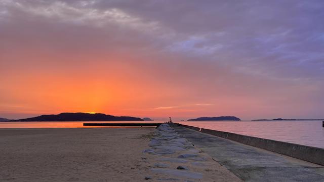 The sun has just set on the beach and the sky is orange and pink.