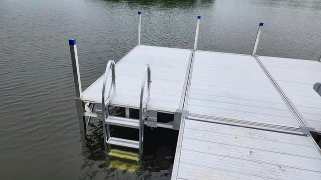 A dock in a lake, aluminum panels, a swimming ladder.