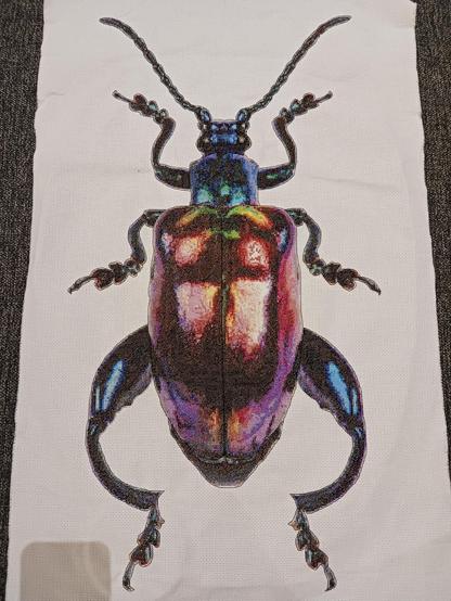 Large cross stitch of a purple jewel beetle.