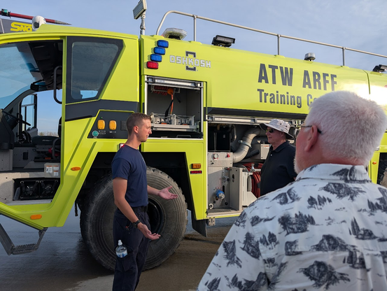An instructor talking to us and explaining the parts of the airport fire vehicle.