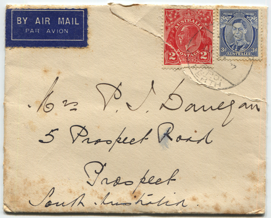 Photograph of the front of a hand-addressed envelope with two or three stamps.