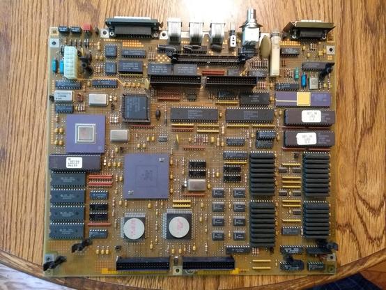 A large golden circuit board with a variety of chips spanning through-hole DIP, PGA, and surface mount technologies, including several ceramic chips with metal caps.  It has a dizzying array of connectors, from board-to-board to board-to-wire (including Mini-Fit and IDC ribbon), and then back panel connections.  The components are laid out assiduously in rows and columns, and areas of the board that have no components have a rectilinear grids of copper squares.  It looks like what you think computers should look like, not this modern flim-flammery.