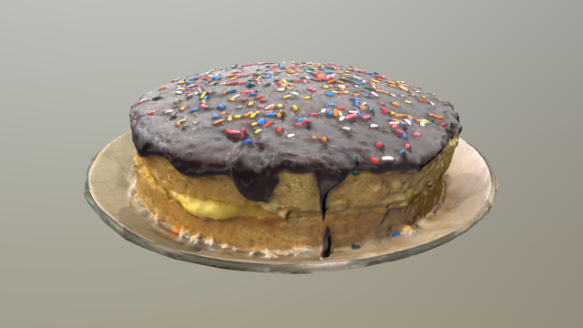 Screenshot of a 3d model of a Boston cream pie.  It has a shiny dark chocolate top with rainbow sprinkles on it, and two layers of yellow cake separated by a layer of cream.