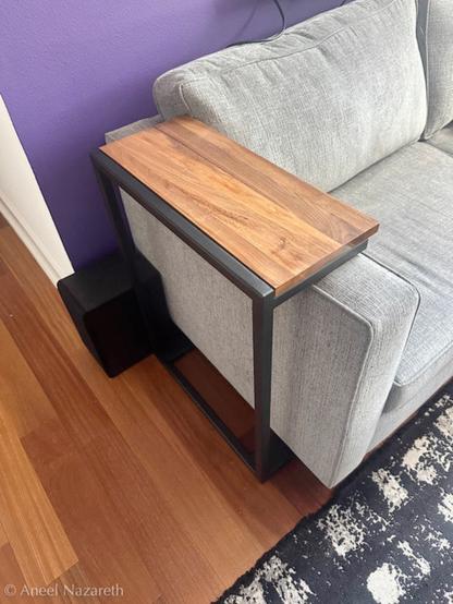 The finished table over the arm of a sofa. The wood is a reddish color, echoing the floor. The frame has been painted matte black