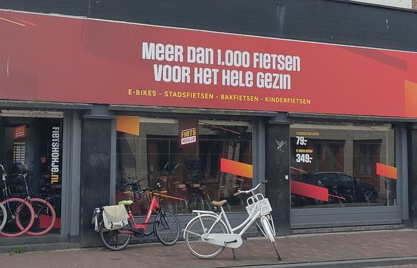 Geveltekst boven de etalage van een fietswinkel: 
Meer dan 1.000 fietsen voor het hele gezin