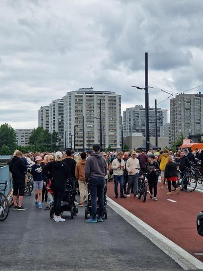 Valokuva Merihaansillalta. Sillalla on suuri määrä ihmisiä. Joillain on lastenvaunuja ja pyöriä kanssa. Taustalla näkyy Merihaka.