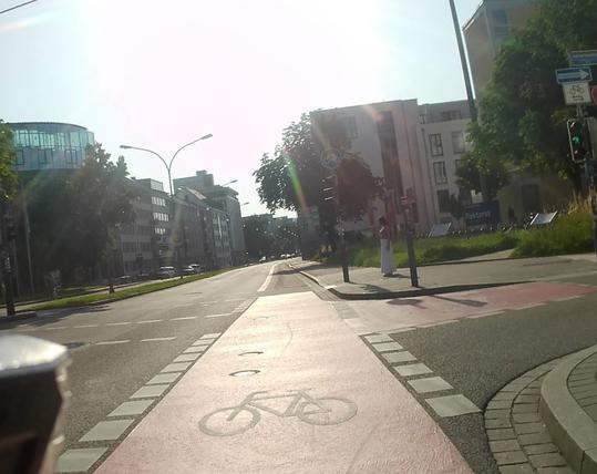 Blick vom Radfahrstreifen auf die Kreuzung. Die Sonne blendet ein wenig. Rechts besagte Radaufstellfläche.