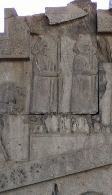 relief of two men with spears and large domed shields covered with lines running parallel to the rim
