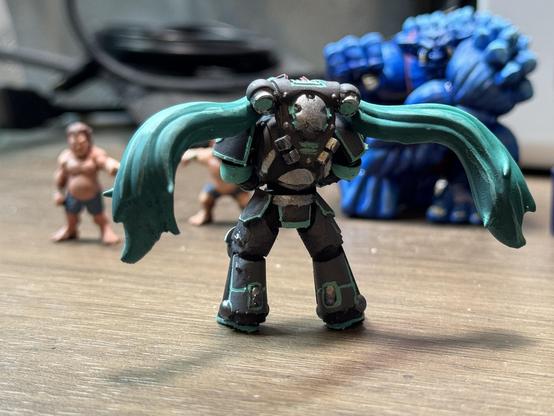 The back of space marine Miku. Standing now faced towards the out of focus Rumbleslam wrestlers.