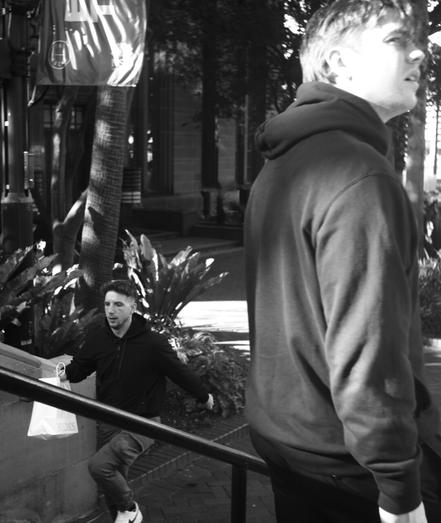 Two young men pass each other on the stairs, one staring out into space and the other jogging up stairs at speed.