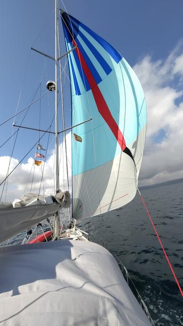 Yacht auf dem Atlantik, gezogen von einem mächtigen Schwachwind-Segel. Blauer Himmel und Quellwolken