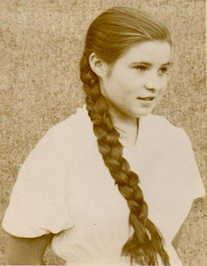 A b/w photo of a young lady with a long braided hair and a sharp look.