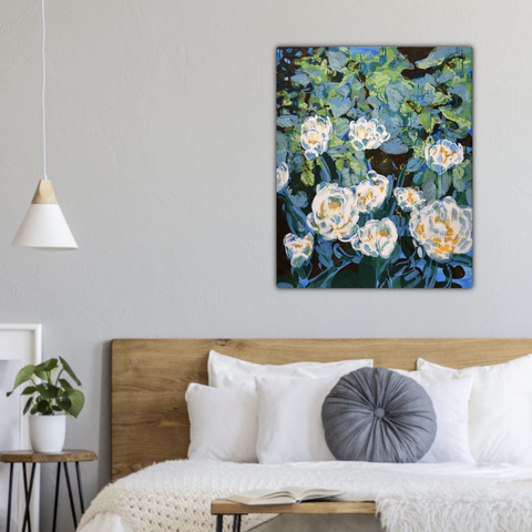 A mock-up of how an abstracted painting of white tulips in a swirl of teal, blue, and green foliage would look like hanging on a white wall behind a wooden headboard and bed with white linen, along with a single white hanging lamp and a couple of wooden end tables with a plant and books on them.