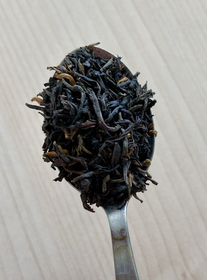 Teeblätter auf einem Teelöffel über einem hellen Tisch